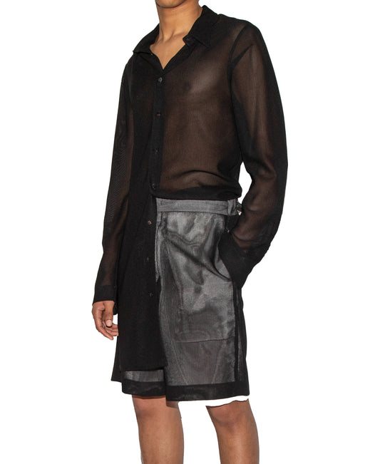 Person wearing a black sheer shirt and skirt set on a white background
