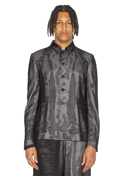 Person wearing a black textured jacket and shorts on a white background