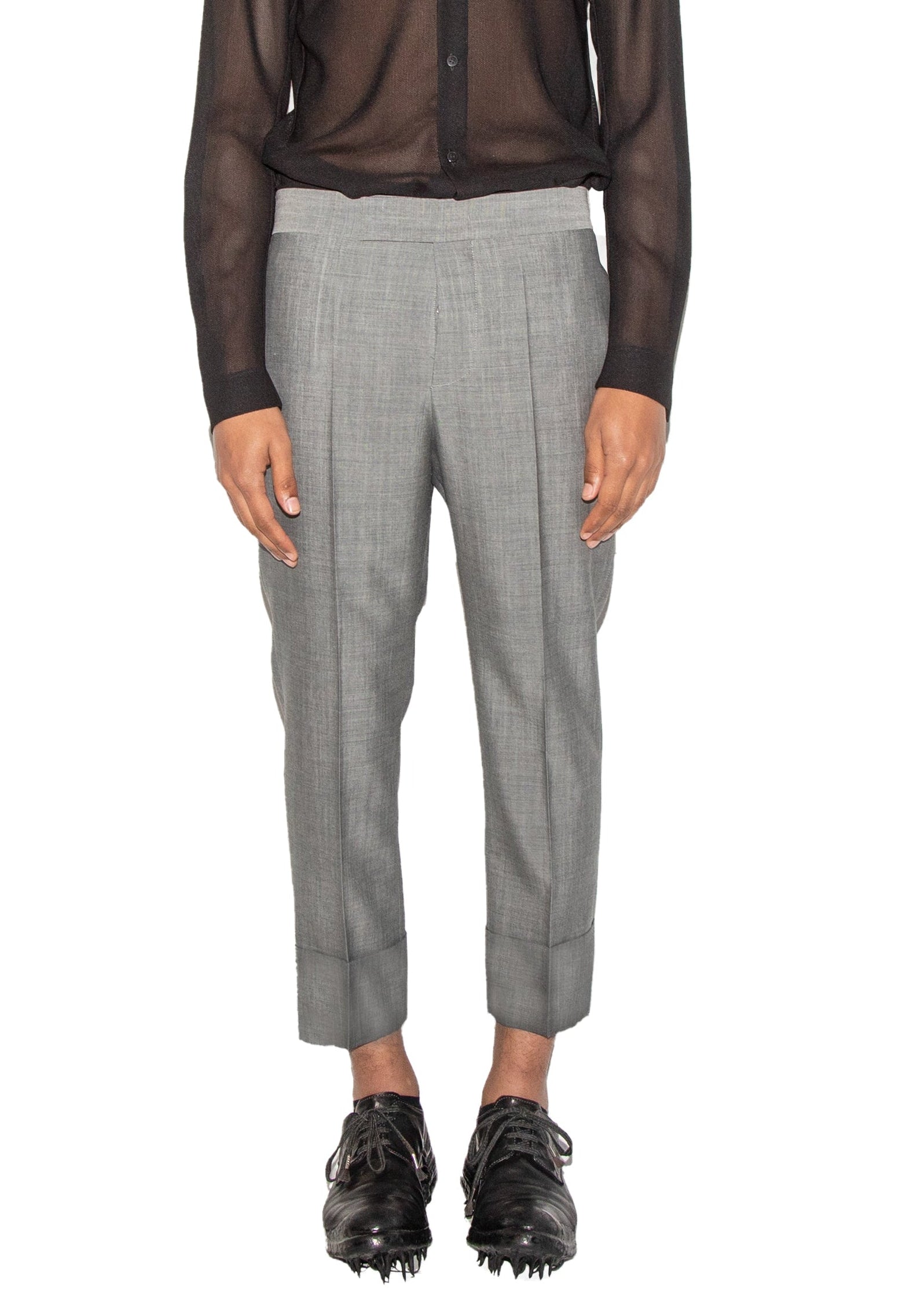 Person wearing a sheer brown shirt over a black shirt with gray pants on a white background