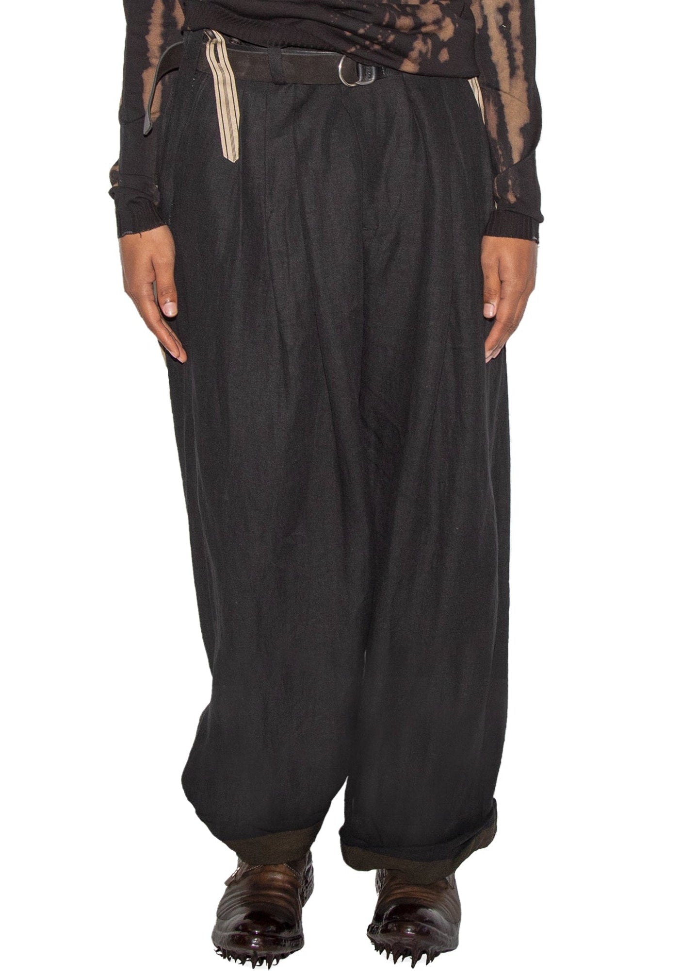 Person wearing a black distressed long-sleeve shirt and wide-leg pants on a white background